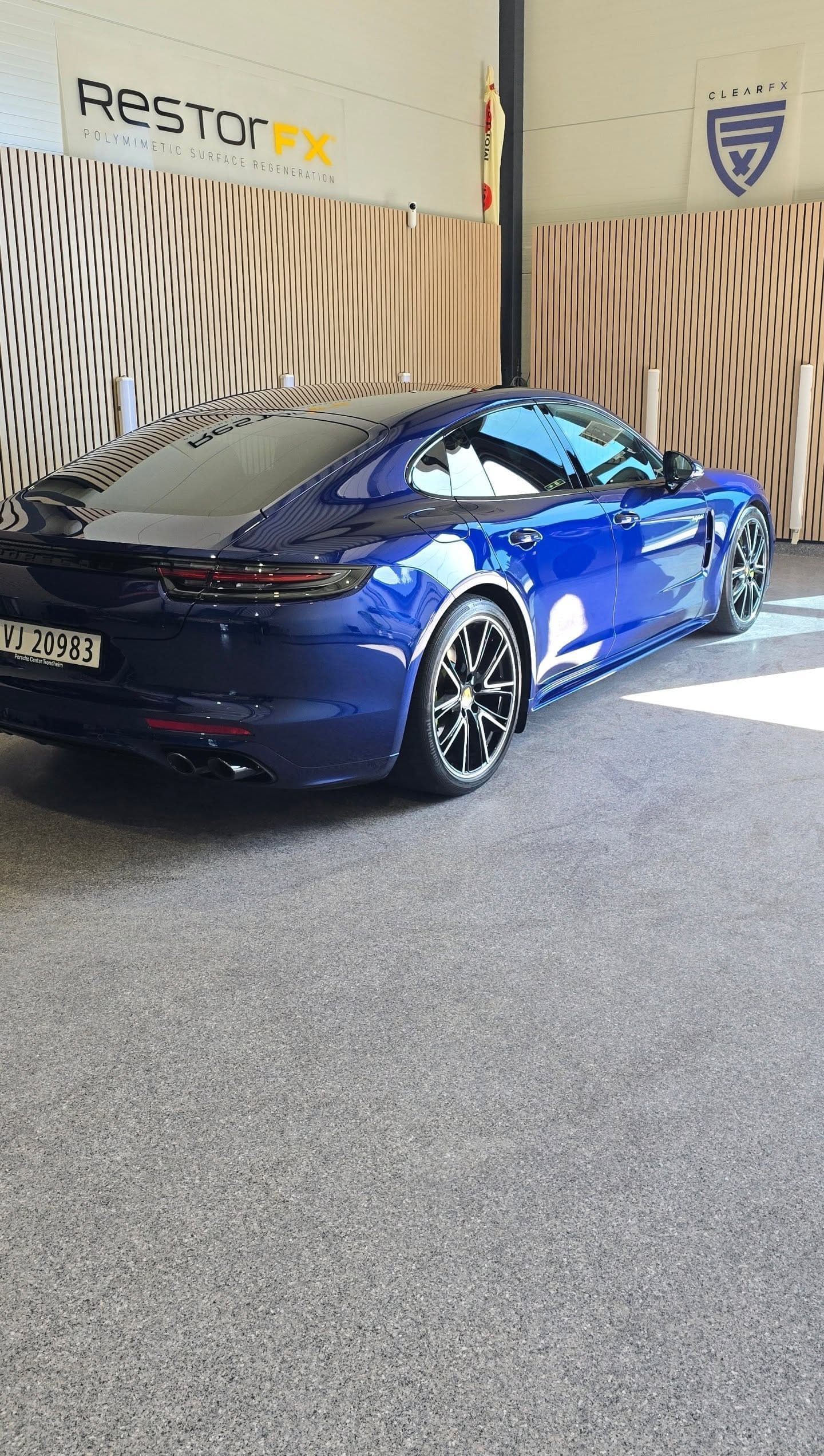 Mørkeblå Porsche Panamera foran RestorFX- og ClearFX-bannerne i studioet