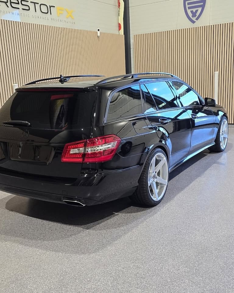 Svart Mercedes-Benz stasjonsvogn som speiler takplatene i studioet