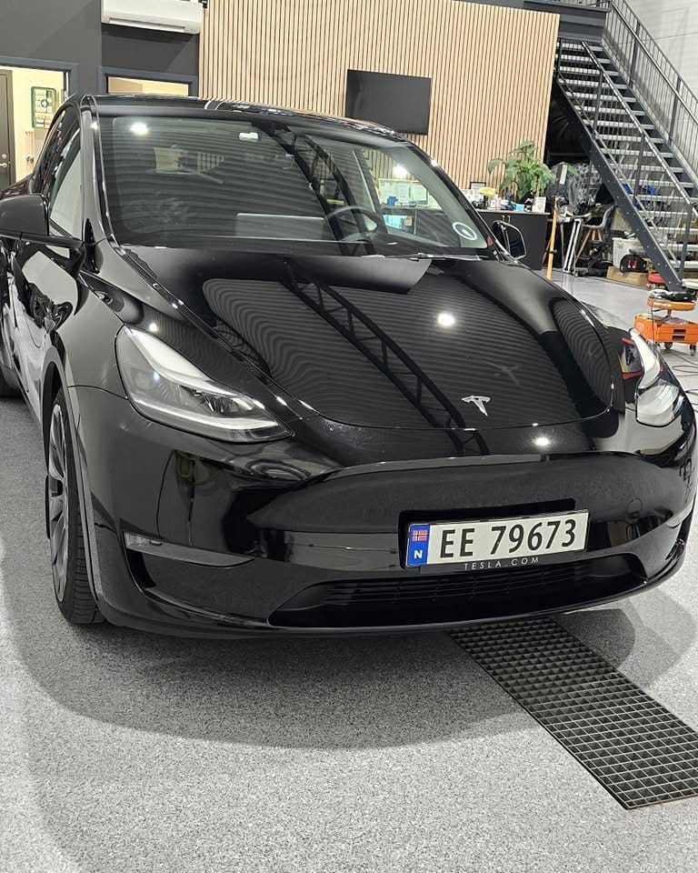 Svart Tesla Model Y med coatet panser og front i studioet